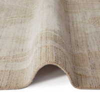 beige abstract rug partially folded on a white floor