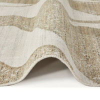 ivory mink abstract rug partially folded on a white floor