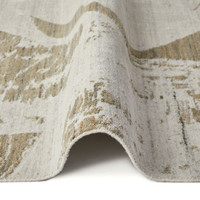 ivory mink abstract rug partially folded on a white floor