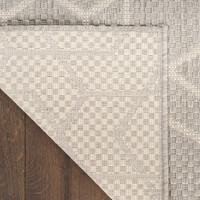 grey geometric indoor outdoor rug folded on wood floor