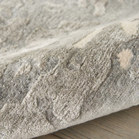 sand abstract rug partially rolled on wood floor