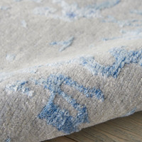 grey blue abstract rug partially rolled on wood floor