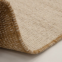 gold flatweave wool rug partial fold on white floor