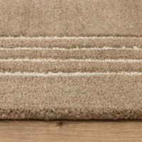 Close-up of the border design on a plush cocoa brown wool rug featuring three thin off-white woven lines along the edge.