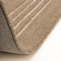 A folded corner of the Orlo cocoa brown wool rug, showcasing the premium woven backing and deep pile thickness.