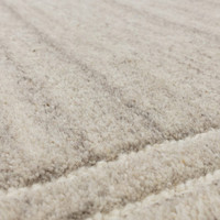 Macro view of a luxury grey wool area rug, emphasizing the soft flecked wool texture and premium hand-woven fiber detail.
