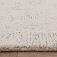 Close-up of the woven edge on a white and black wool rug, showcasing a dense plush pile and clean monochrome border stitching.
