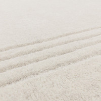 Macro texture shot showing the dense, high-quality tufted pile and soft fibers of a modern ivory wool area rug.