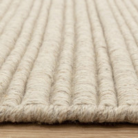 Side view detail of a textured cream wool rug highlighting its thick, durable linear construction.