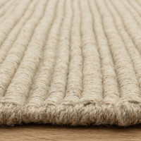 Side view detail of a textured neutral wool rug highlighting its thick, durable linear construction.