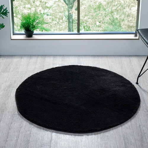 plain black rug circle in a living space with a window