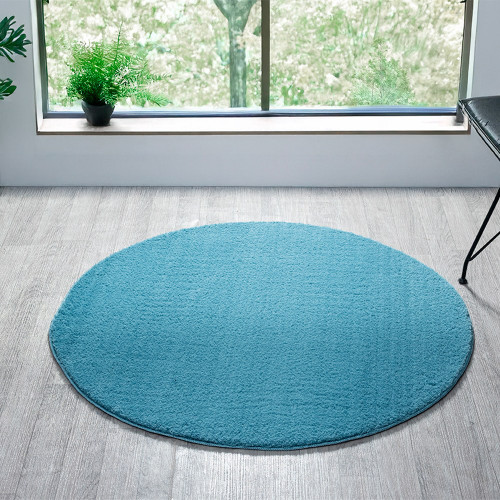 plain teal rug circle in a living space with a window