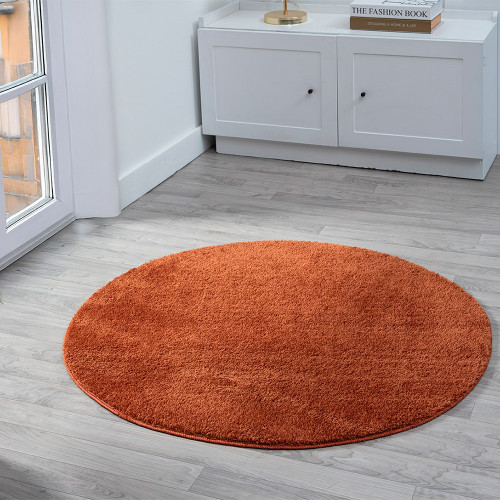 plain terracotta rug circle in a living space with a window