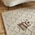 taupe wool rug closeup in a living room with natural decor