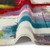 multicolour abstract rug partially folded on a white floor