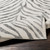 charcoal zebra pattern rug closeup corner fold on wood floor