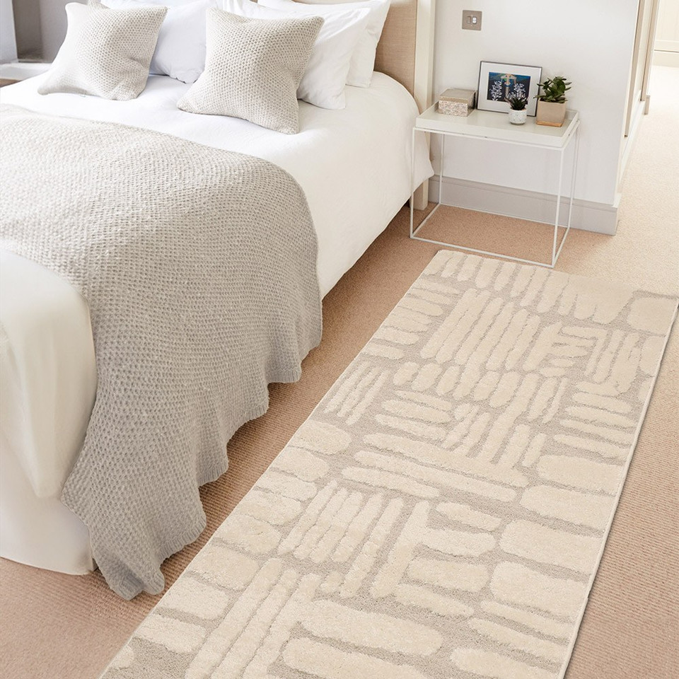 Ava Pave Cream Rug Runner in a bedroom beside a bed