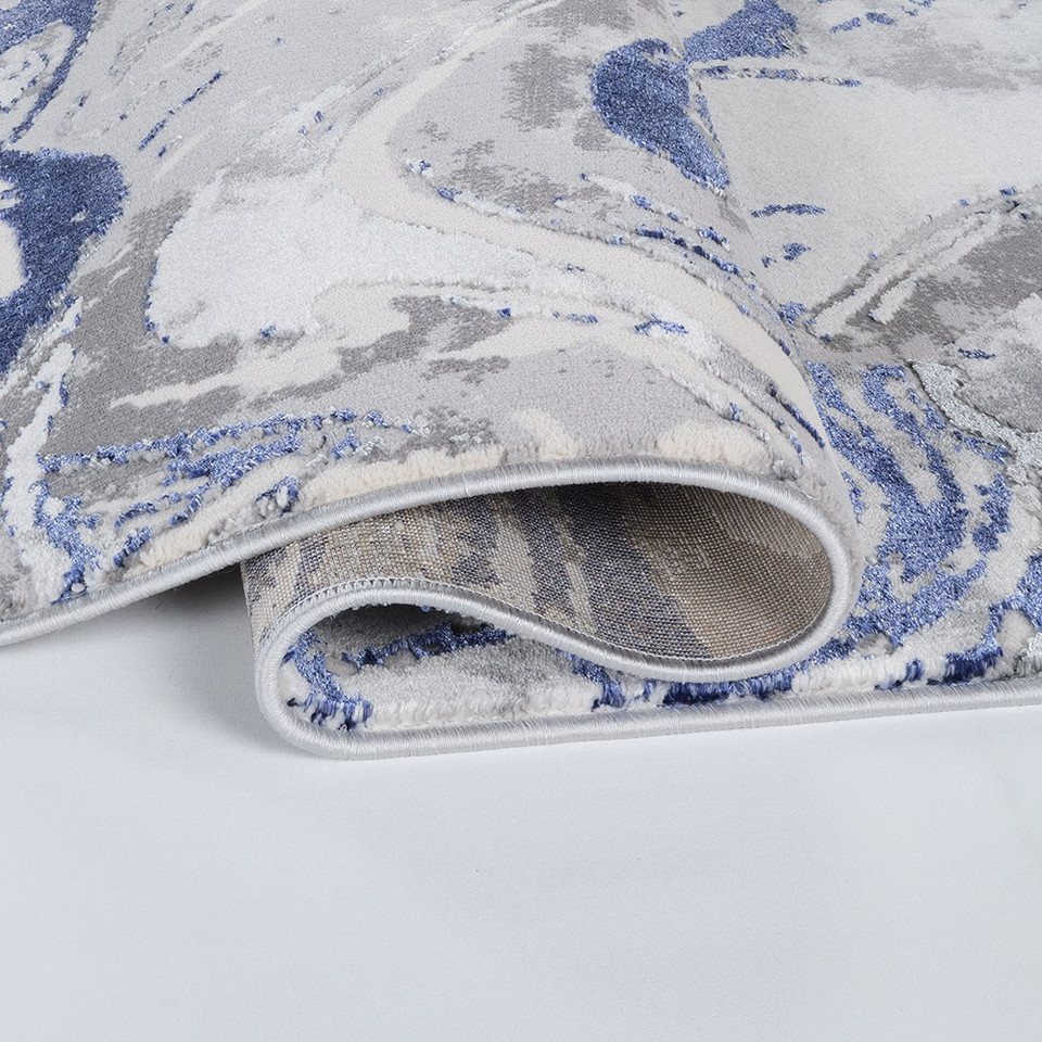 navy grey abstract rug folded on a white floor