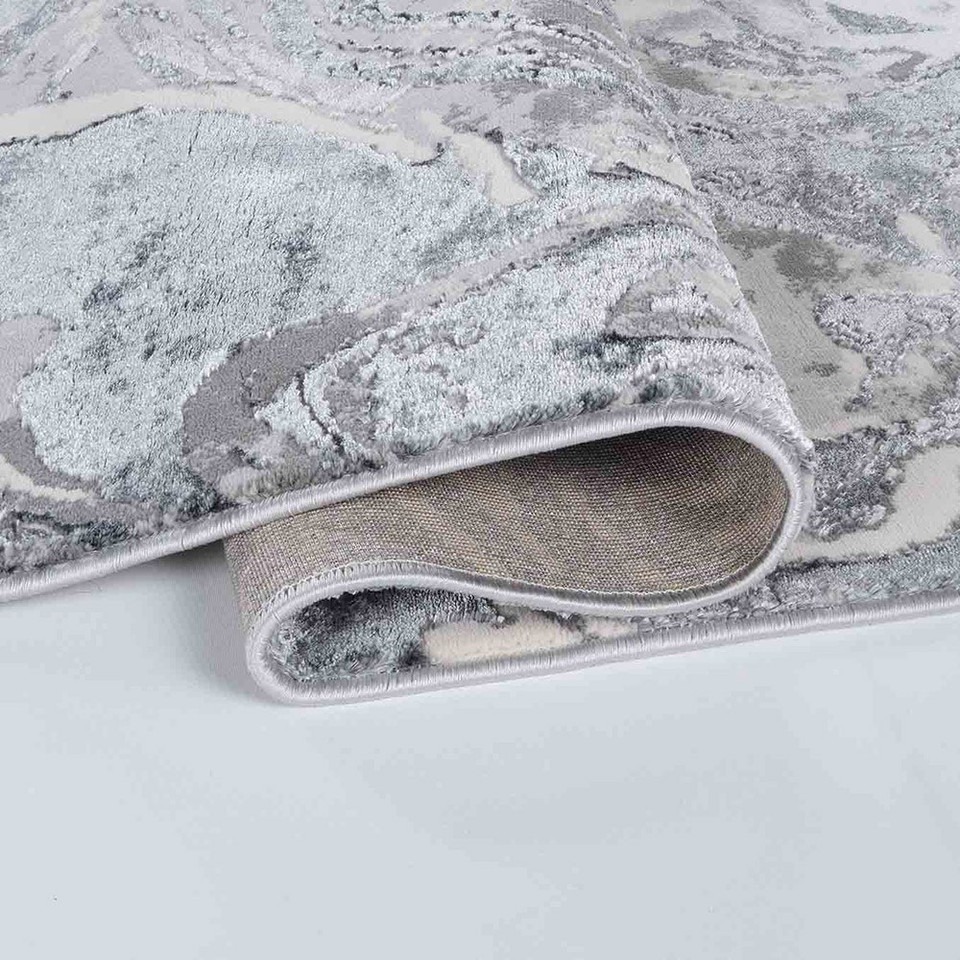 silver abstract rug folded on a white floor