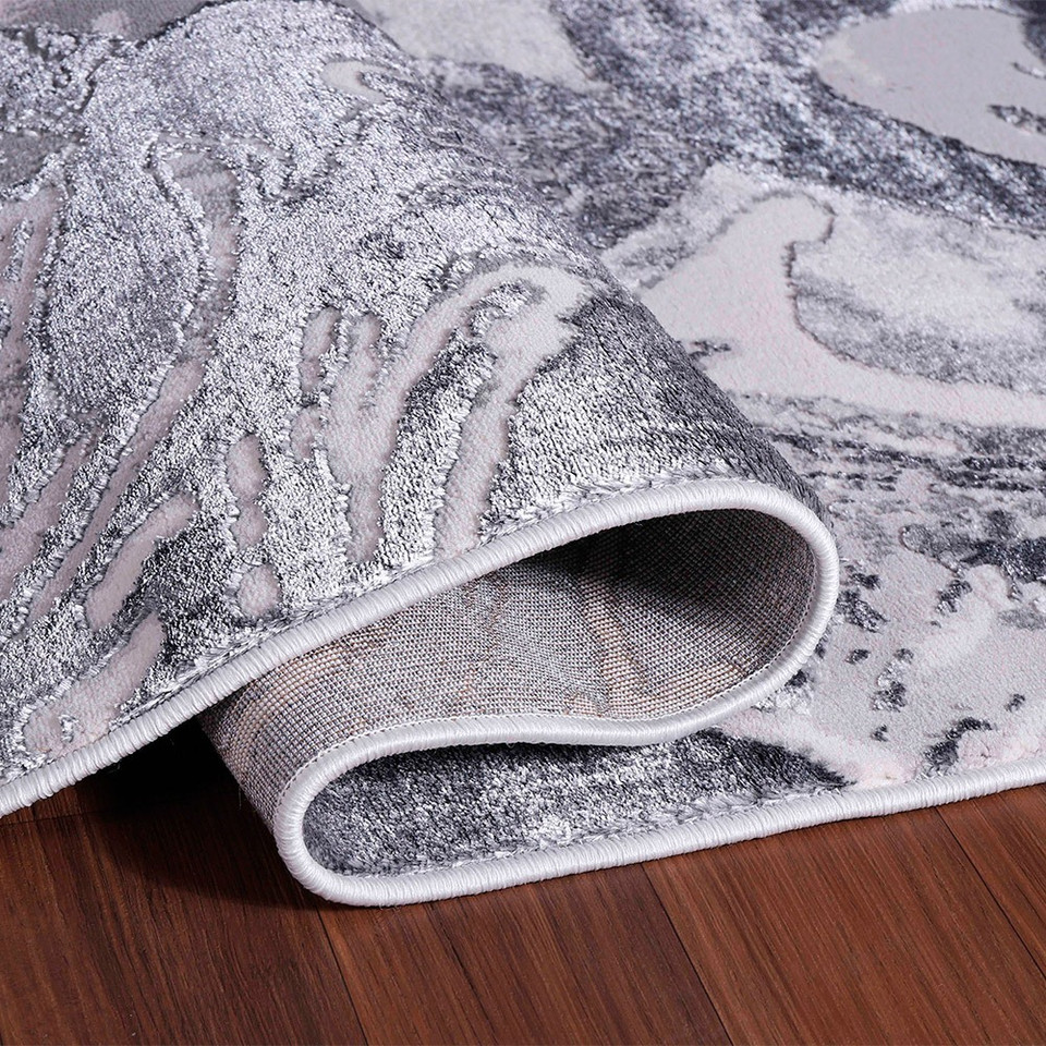 silver abstract rug folded on a wooden floor