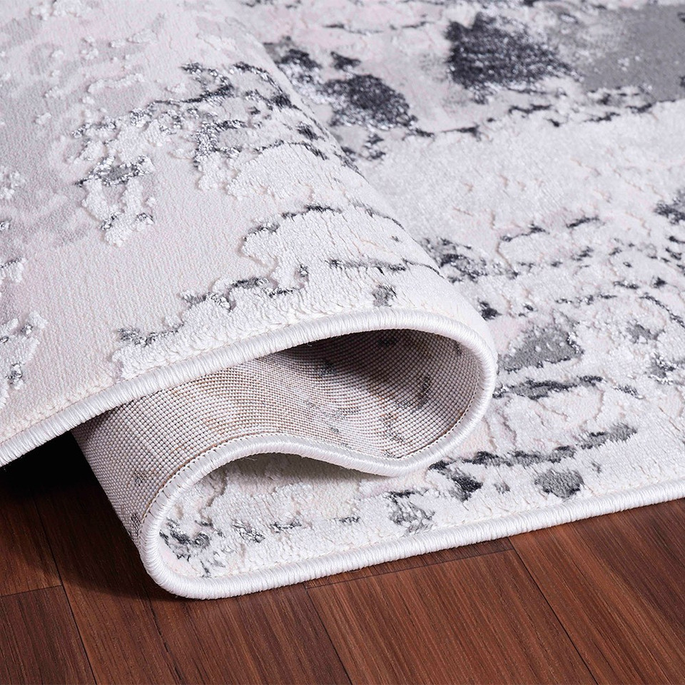 grey abstract rug folded on wooden floor