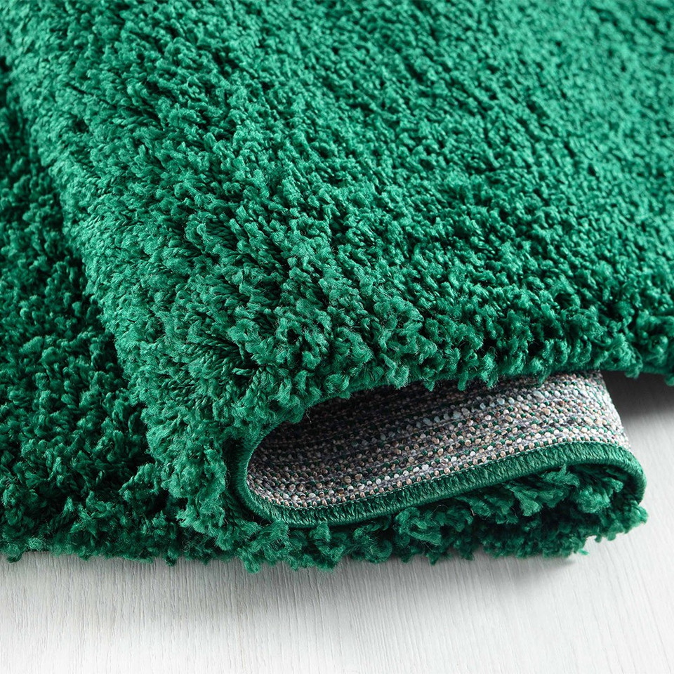 plain shaggy emerald circle rug folded on wooden floor