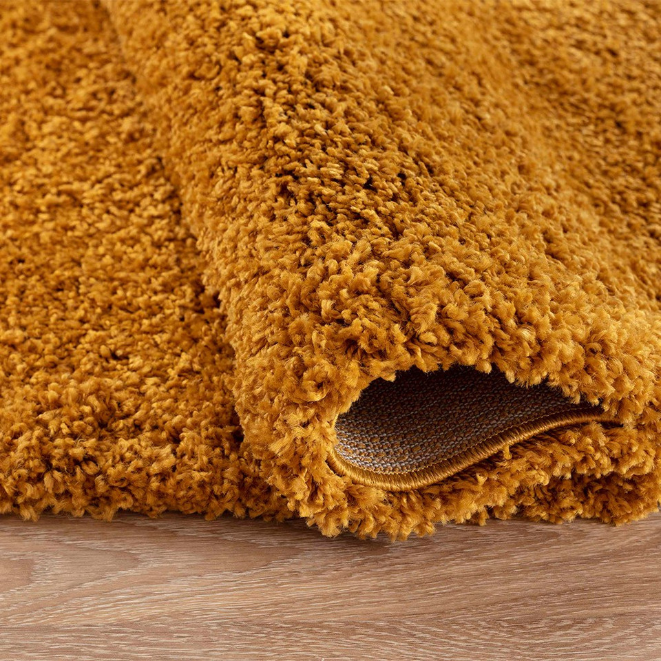 plain shaggy gold rug runner folded on wooden floor
