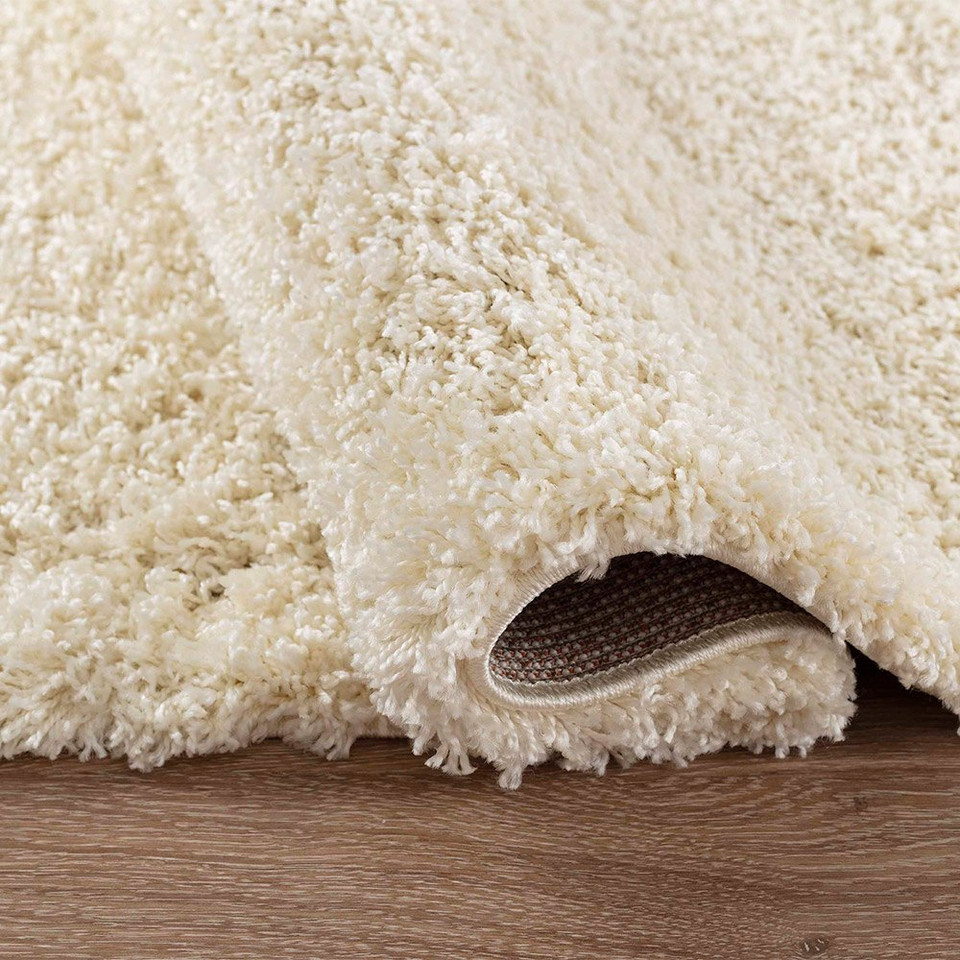 plain shaggy ivory rug folded on a wooden floor