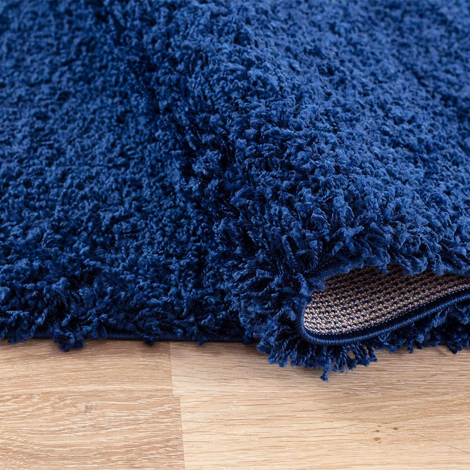 plain shaggy navy rug folded on a wooden floor