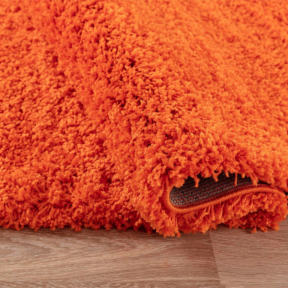plain shaggy orange rug runner folded on wooden floor