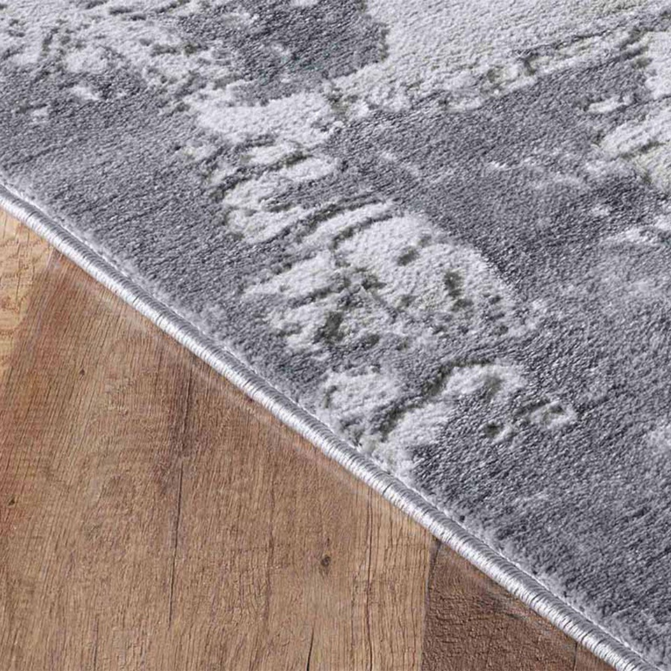modern abstract abrasion grey rug closeup edge on a wooden floor