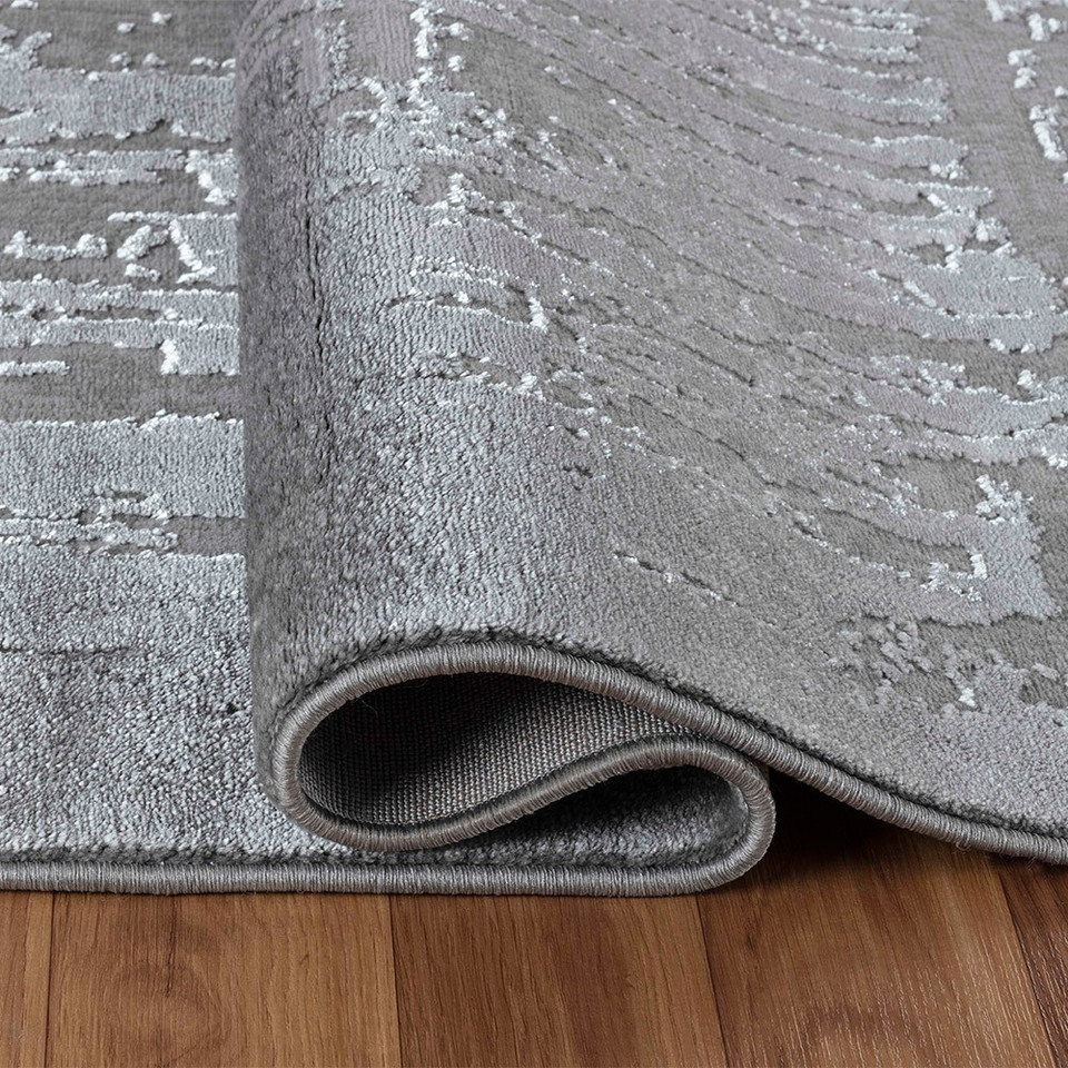 modern abstract abrasion grey rug folded on a wooden floor
