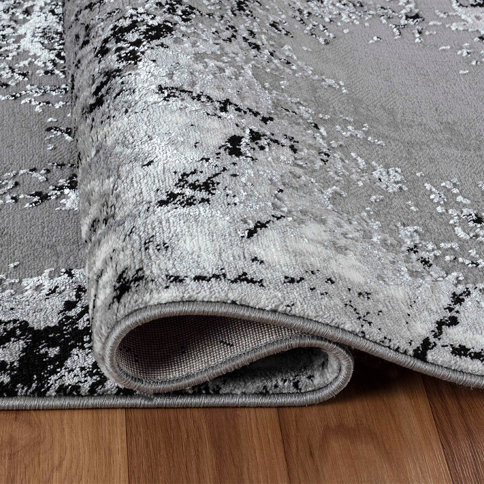 modern abstract acrylic black rug folded on a wooden floor