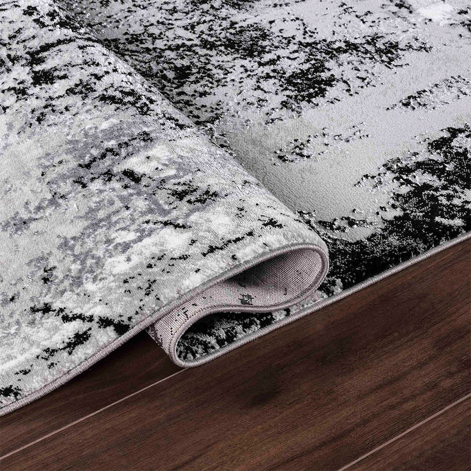 modern abstract acrylic black rug folded on a wooden floor