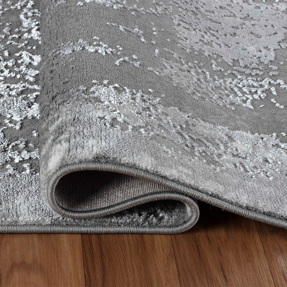 modern abstract acrylic grey rug folded on a wooden floor