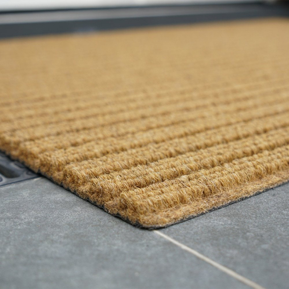 beige coir doormat closeup corner infront of doorway outdoors