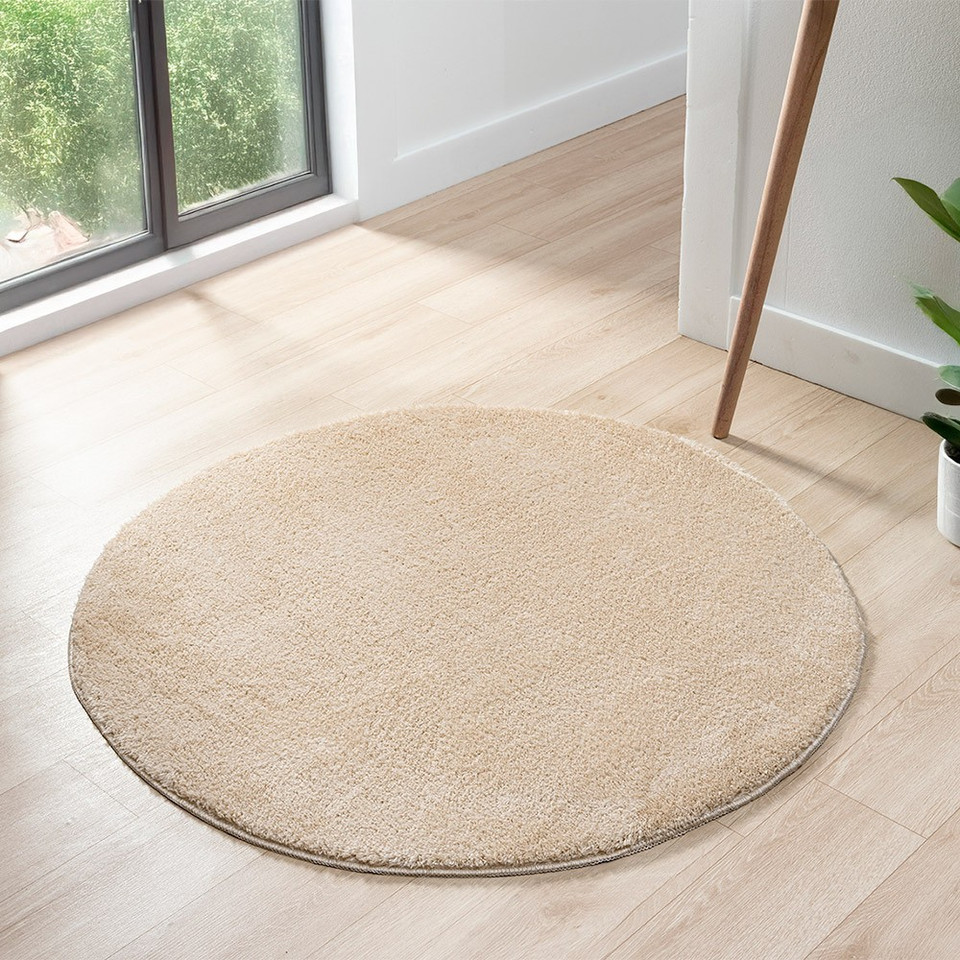 plain beige rug circle in a living space with a window