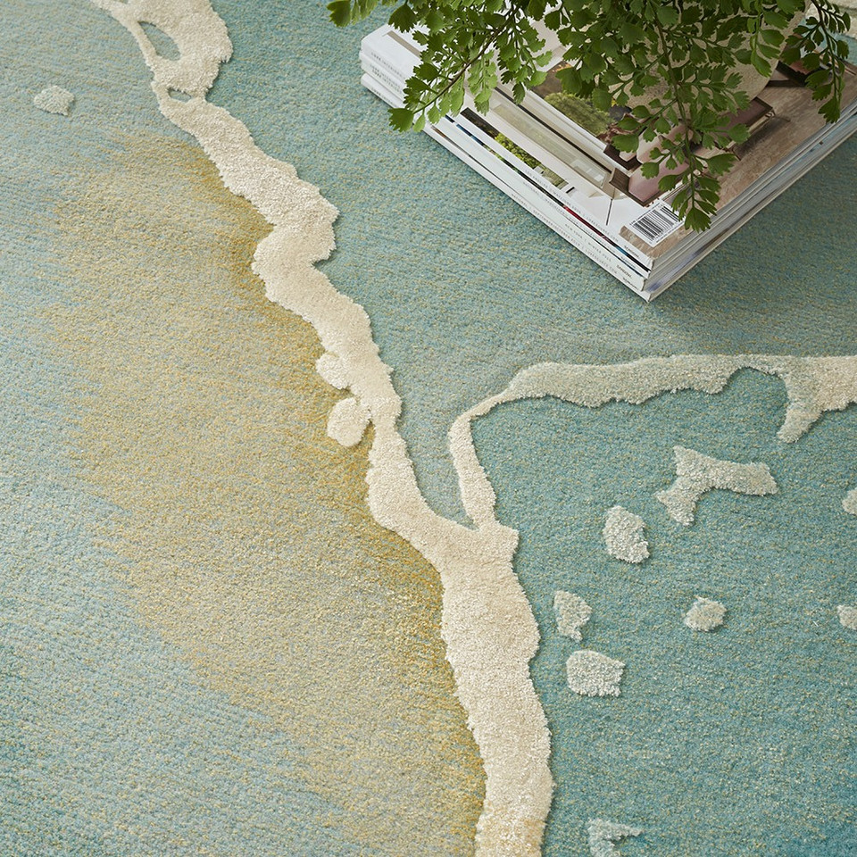 grey seafoam abstract rug closeup of pattern with a pile of books and plant pot