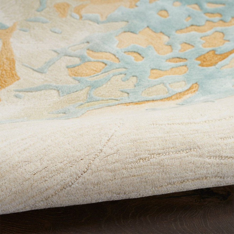 sand blue abstract rug partially rolled on a dark wood floor