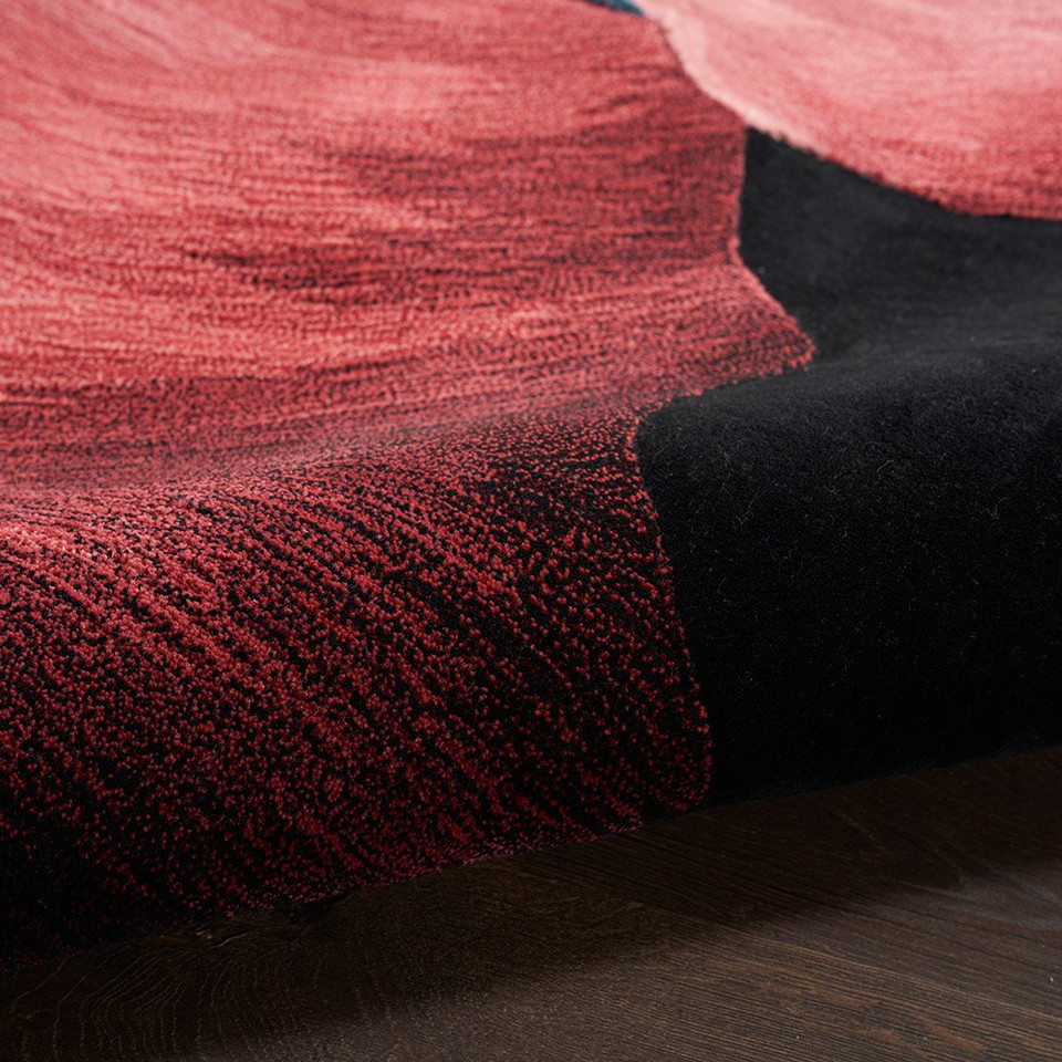 black abstract rug partially rolled on a dark wood floor