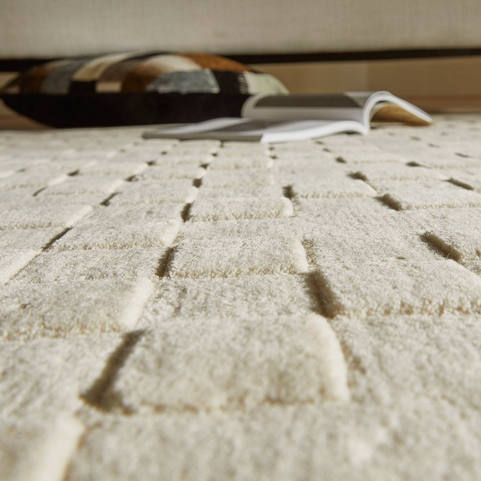 ivory wool rug closeup under sofa with book