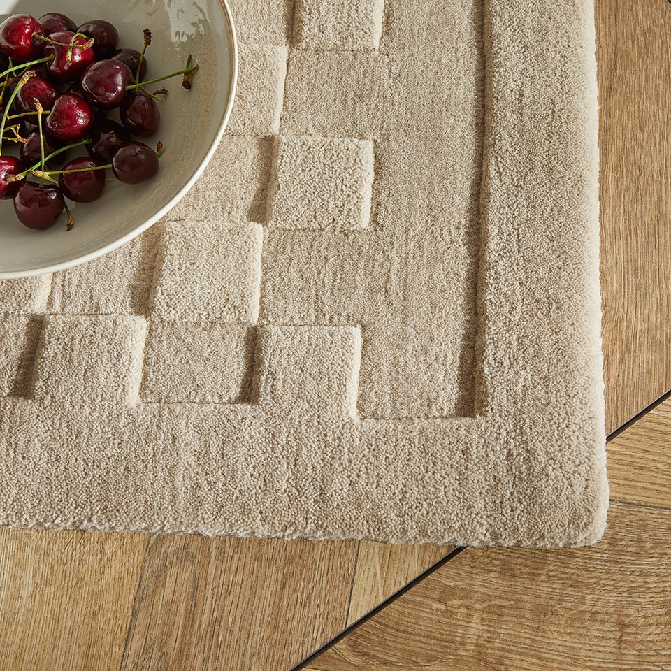 taupe wool rug closeup corner with bowl of fruit