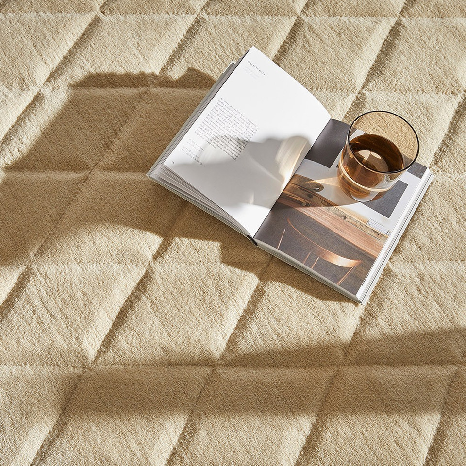 beige wool rug closeup with book and glass