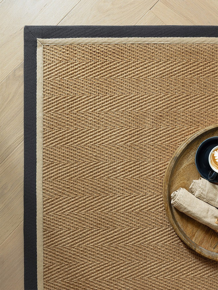 herringbone slate cream jute rug closeup corner with plate on wood floor