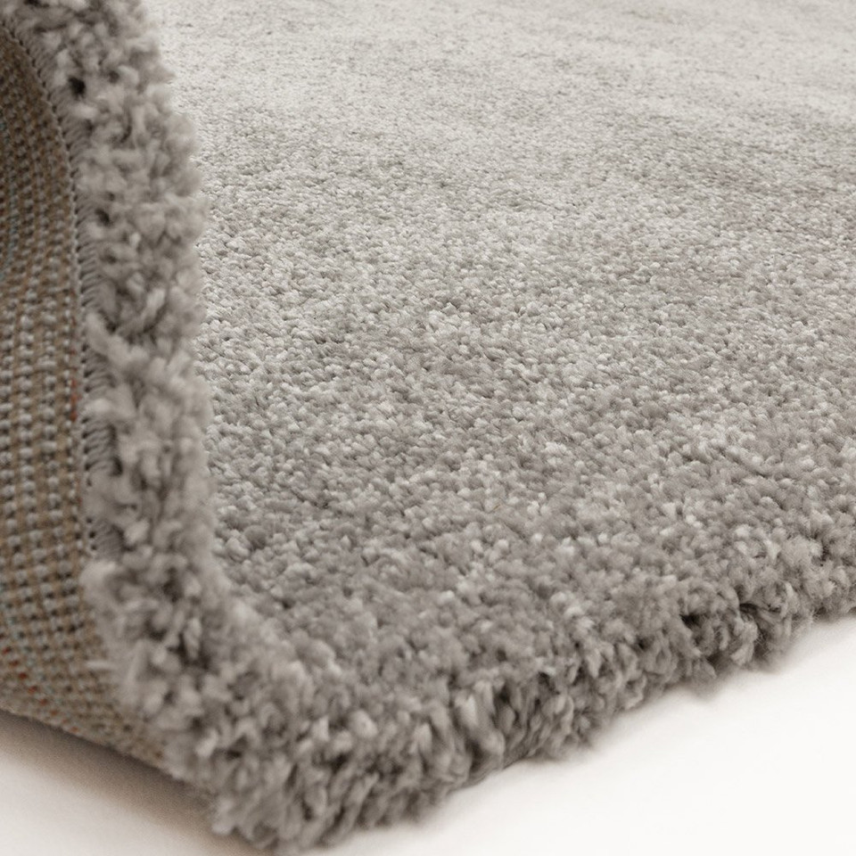 silver shaggy rug partially folded on white floor
