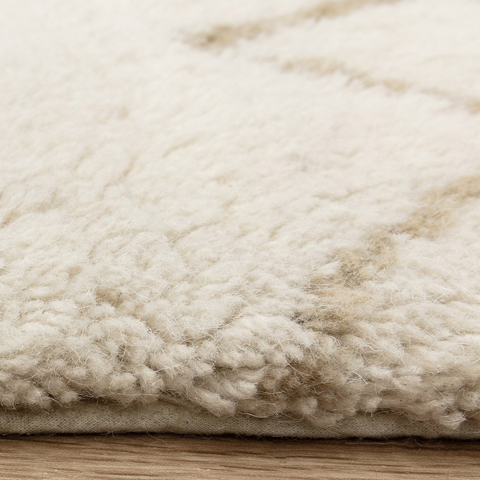 cream berber shaggy wool rug closeup edge on wood floor