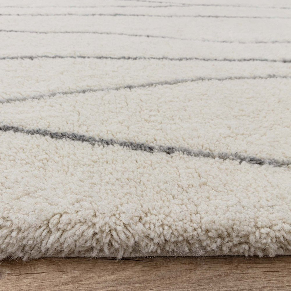 cream berber shaggy wool rug closeup edge on wood floor