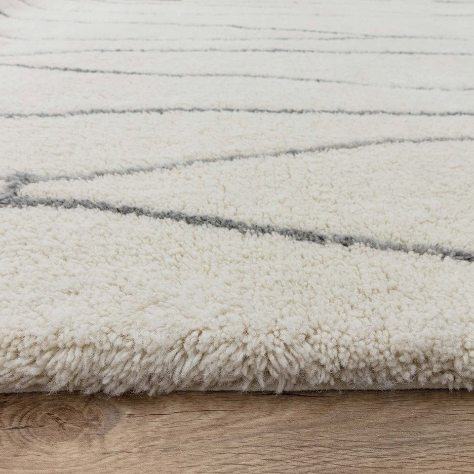 cream berber shaggy wool rug closeup edge on wood floor