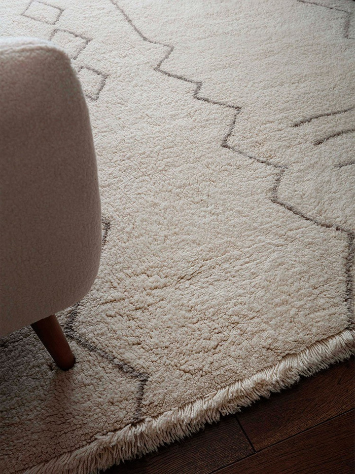 cream berber shaggy wool rug closeup on wood floor
