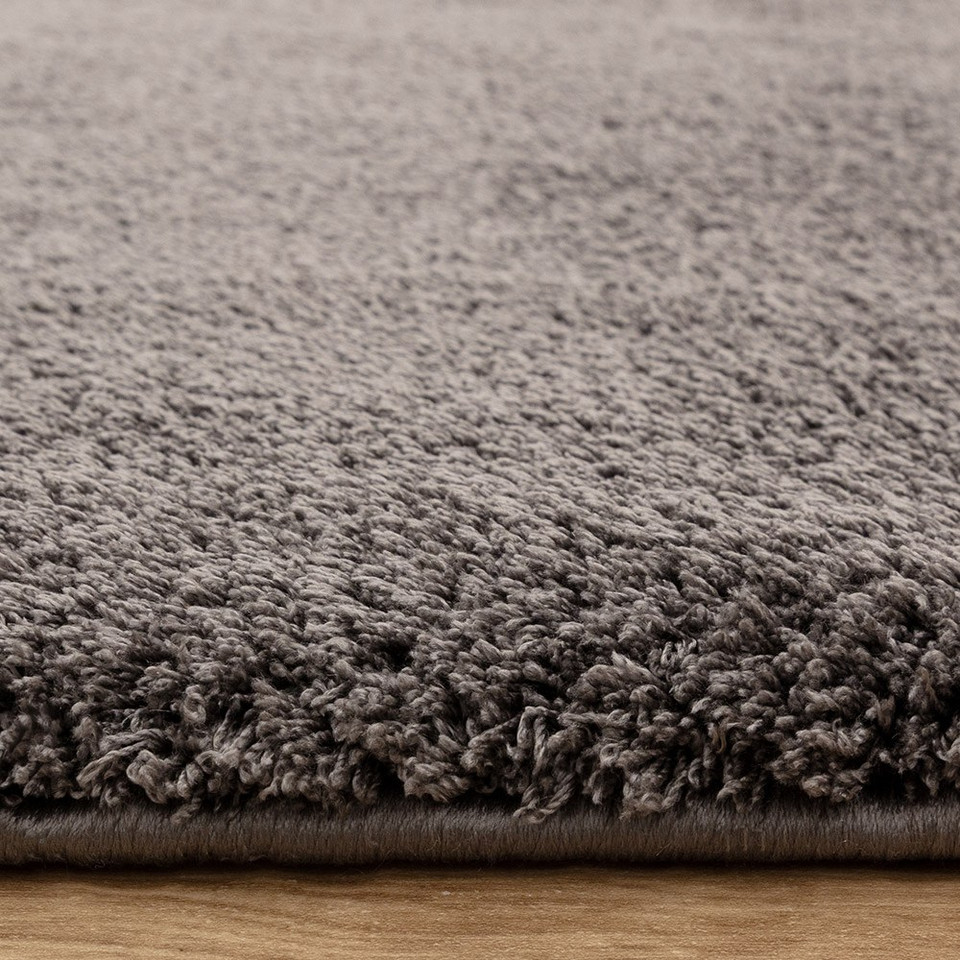 charcoal plain shaggy rug closeup edge on wood floor
